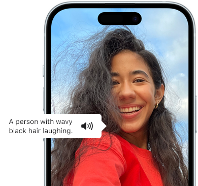 iPhone 15 waarop de VoiceOver-feature informatie geeft over een foto van een lachende persoon met golvend zwart haar