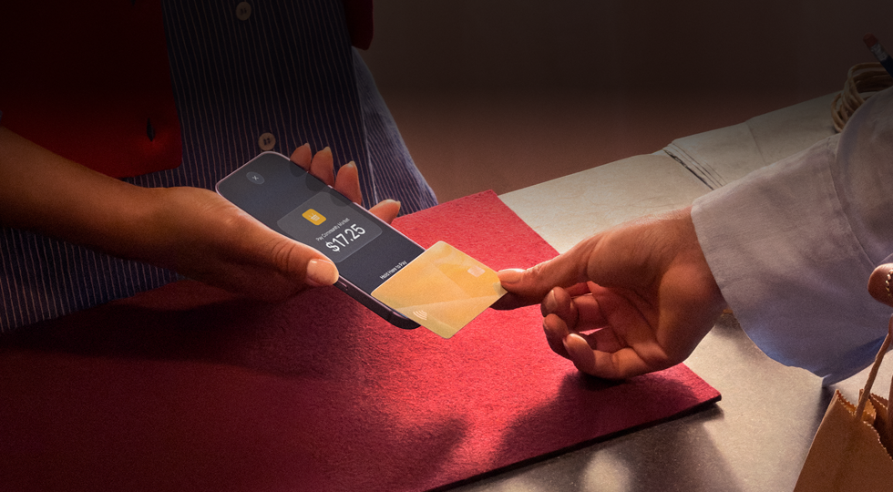 Een hand die een creditcard tegen een iPhone tikt om een transactie te voltooien