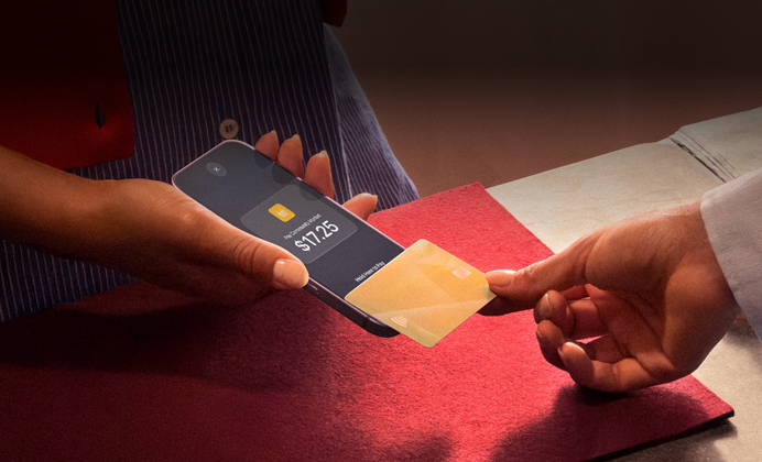 Een hand die een creditcard tegen een iPhone tikt om een transactie te voltooien