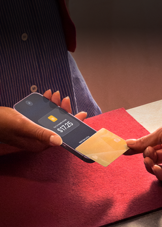 Een hand die een creditcard tegen een iPhone tikt om een transactie te voltooien
