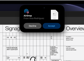 Op het scherm is het Dynamic Island te zien met een AirDrop-verzoek in een klein venster boven een geopend Adobe Acrobat-bestand