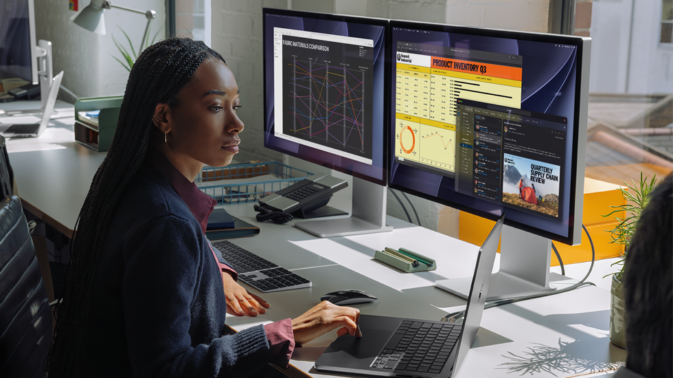 A woman working at her desk with MacBook Pro connected to two external displays