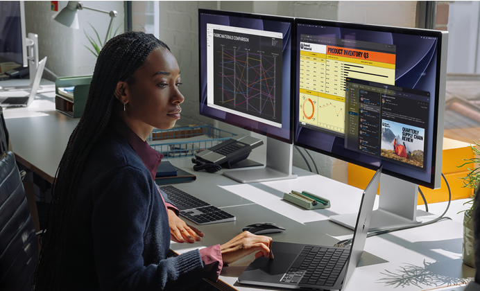 A woman working at her desk with MacBook Pro connected to two external displays