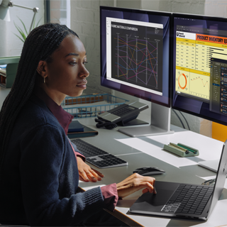 A woman working at her desk with MacBook Pro connected to two external displays